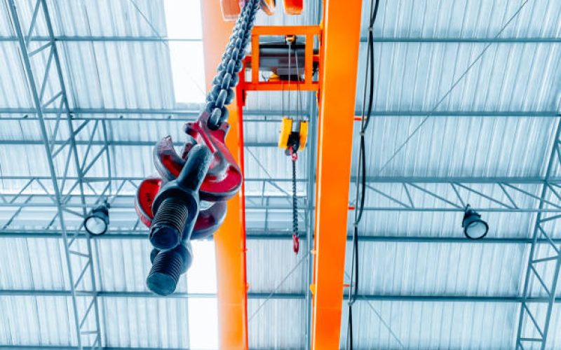 Overhead crane inside factory building, industrial background.